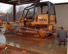 Using a de-mucking system on a dirty bulldozer.
